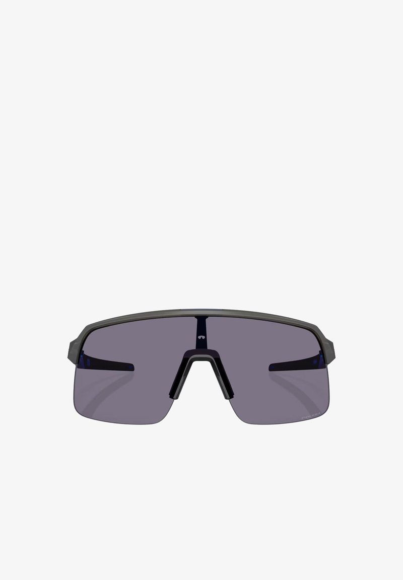 Occhiali da sole sportivi con una grande lente a scudo grigio scuro, una montatura nera opaca e accenti blu sulle astine. Design leggero e aerodinamico.