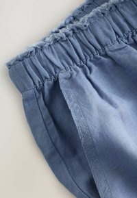 Șorturi din in albastre cu un brâu elastic, având o margine superioară volanată și cusături laterale plate. Textură netedă, material ușor.