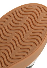 Gummisula med tan seglisk mönster och rektangulära texturerade greppinslag för halkskydd.