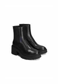 Bottines en cuir noir avec des panneaux latéraux élastiques, semelle en caoutchouc noir épaisse, bouts ronds et texture lisse. Idéales pour un usage décontracté.