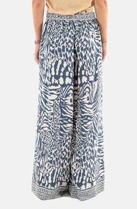 Pantaloni larghi a righe blu e crema con vita elastica e bordo ispirato al tribale all'orlo, che mostrano un mix di motivi animali.