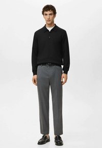 Polo a maniche lunghe nere con collo a rever, abbinata a pantaloni grigi su misura e scarpe slip-on nere.