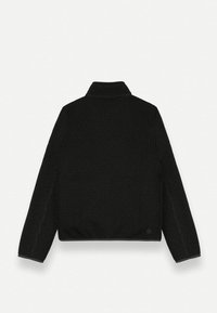 Melnā ribota augsto apkakliņu džemperis ar īsu, kasti līdzīgu griezumu. Iezīmē augstu apkakli un garas piedurknes. Tekstūrēts audums rada dziļumu.