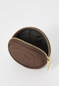 Rundes braunes Täschchen aus texturiertem Stoff, mit einem goldenen Reißverschluss und einem schwarzen Innenraum. Die Außenseite weist ein dezentes, geprägtes Design auf.