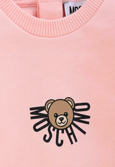 Felpa rosa con design di un orso in stile cartone animato e testo nero "MOSCHINO", con colletto a coste per un tocco di texture in più.
