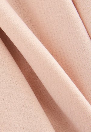 Ljusrosa tyg med en mjuk, texturerad yta, som har subtil ojämnhet i vävningen, visad i vikta lager.
