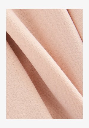 Tissu rose clair avec une surface douce et texturée, présentant une subtile irrégularité dans le tissage, affiché en couches repliées.