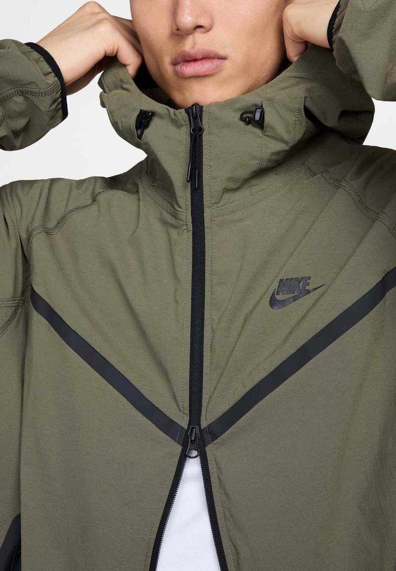 Jasnozielona, lekka kurtka z wysokim kołnierzem, czarnym zamkiem błyskawicznym i podkreślonymi czarnymi ukośnymi paskami. Posiada logo Nike na piersi.