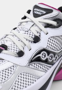 White athletic shoe with a mesh upper, black and gray accents, and pink detailing. Features contrasting textures and a streamlined design.