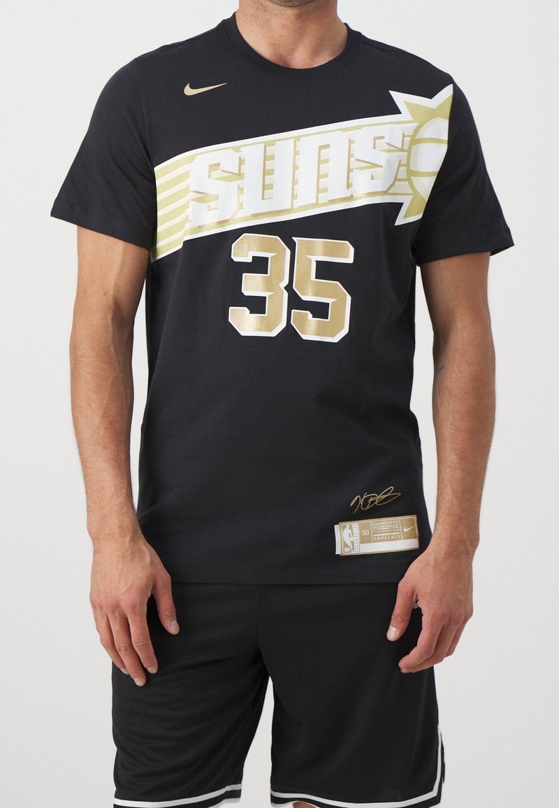 Homme portant un maillot de basket Suns noir avec le numéro 35 et des accents dorés, associé à un short noir avec un liseré blanc.