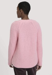 Rosa gestrickter Pullover mit einem gerippten Design, rundem Halsausschnitt und langen Ärmeln. Mit Raglan-Nähten und einer lockeren Passform gestaltet.