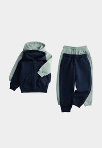 Two children's hooded zip jackets and matching elastic waist jogger pants in navy blue and light green, laid flat on a light background.
