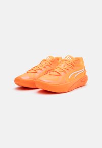 Sapatos atléticos laranja brilhante com parte superior em rede, design texturizado e atacadores proeminentes. Apresenta detalhes brancos ao longo dos lados e da sola.