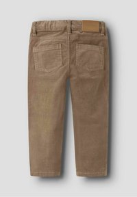 Pantaloni in velluto a coste marroni con vita elastica, due tasche posteriori e una piccola etichetta in pelle color crema sul lato destro dietro.