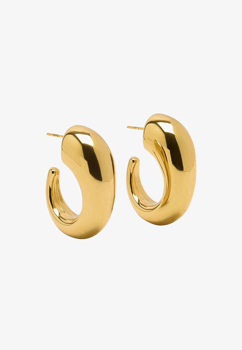 Złote kolczyki w kształcie obręczy o błyszczącym wykończeniu, charakteryzujące się zaokrąglonym, rzeźbiarskim kształtem, który zwęża się ku środkowi z otwartymi końcami.