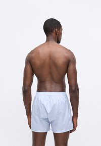 Μπλε και λευκές ριγέ σλιπ με ελαστική μέση. Ελαφρύ ύφασμα, άνετη εφαρμογή και οι ραφές στα πλάγια ορατές στο πίσω μέρος.