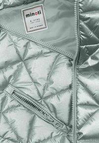 Silberne gepolsterte Jacke mit rautenförmigem Steppmuster, ausgestattet mit einem grauen Reißverschluss und einem Stoffetikett, das die Größe 8-9 Jahre und den Herkunftsort angibt.