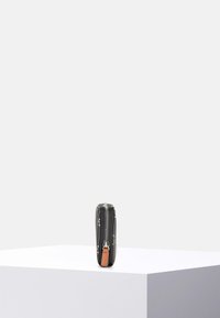 Cartera con cremallera negra con acento de cuero marrón claro, que presenta una cremallera plateada y patrones decorativos sutiles. Forma rectangular compacta.