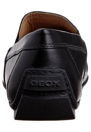 Black leather shoe with a smooth texture, rounded shape, and a rubber sole featuring a "GEOX" logo at the heel. Minimalist design.