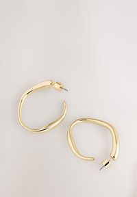 Gold hoop earrings with a smooth, curved design. Features a textured surface and secure post-back closure.