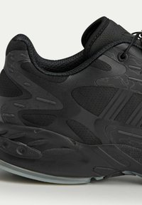Black athletic shoe featuring a textured upper, smooth accents, padded collar, and a flexible rubber sole with detailed tread pattern.