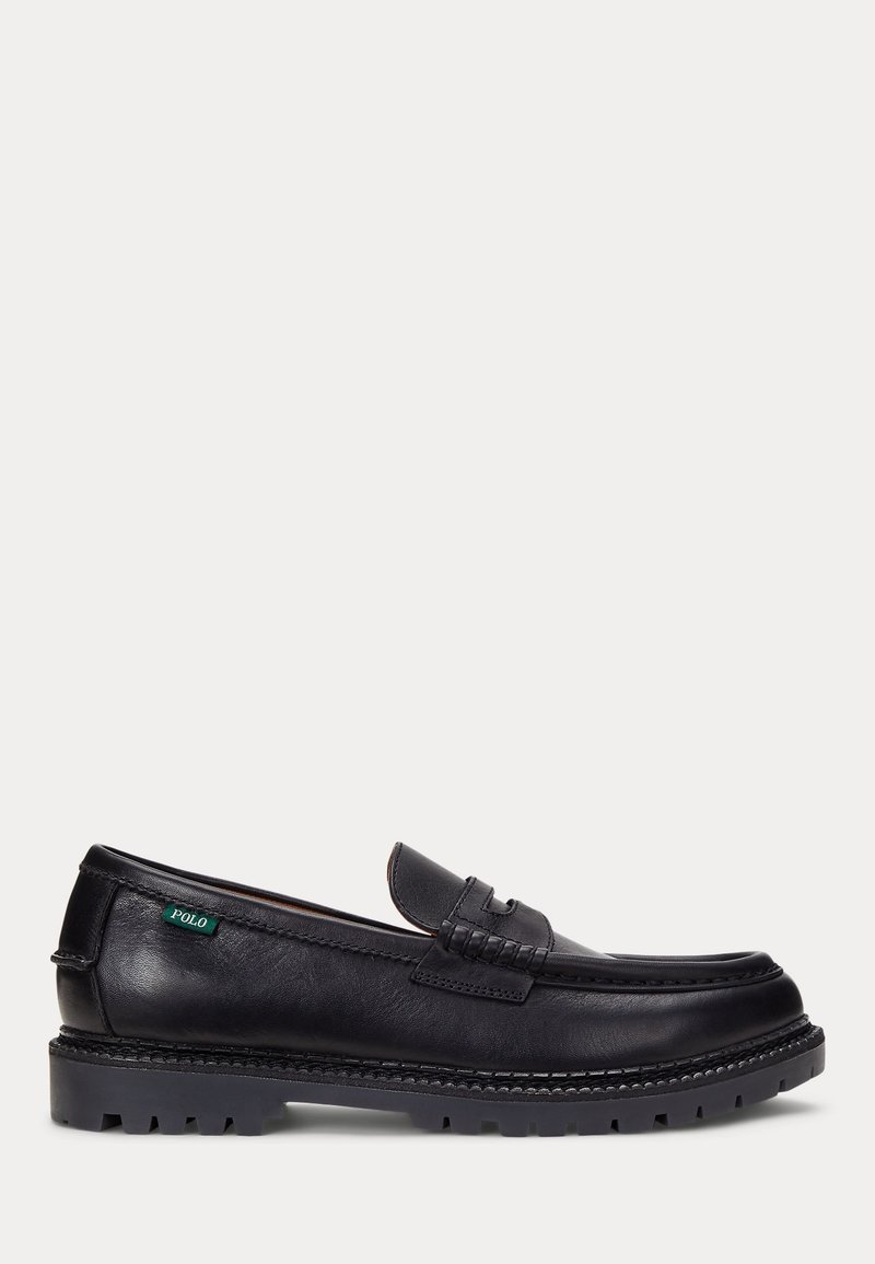 Mocassin en cuir noir avec semelle robuste et étiquette Polo verte sur le côté, présentant des détails cousus et un design sans lacets.