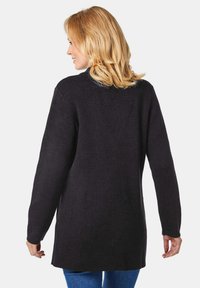 Schwarzer Pullover mit langen Ärmeln aus strukturiertem Material, mit lässiger Passform. Der Rücken zeigt einen geraden Saum und subtile, minimalistische Designdetails.