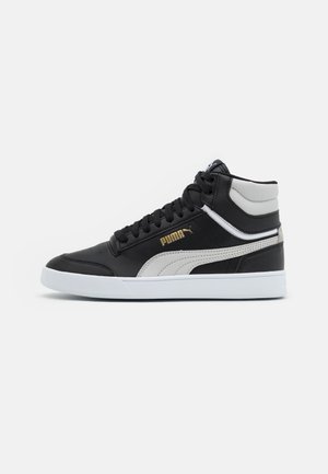 Sort-hvid høj sneaker fra Puma med hvidsål og gyldent Puma-logo på siden, vist fra ydersiden.