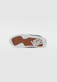 Fekete sneaker talp, textúrált barna gumimintával és fehér "VANS" logóval. Simák a szélek, és jellegzetes mintázatú a talp.