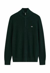 Donkergroen trui met een hoge kraag en halve rits. Geribbelde textuur met een klein logo op de linkerkant van de borst. Lange mouwen, ontspannen pasvorm.