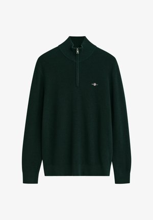 Donkergroen trui met een hoge kraag en halve rits. Geribbelde textuur met een klein logo op de linkerkant van de borst. Lange mouwen, ontspannen pasvorm.