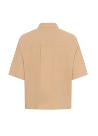 Lyhythihainen vaaleanbeige paita, jossa on kauluspanta ja suora helma. Takapaneelissa on ompeluyksityiskohtia.