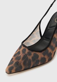 Chaussure à talon haut en imprimé léopard avec un bout pointu, un encadrement noir élégant et un panneau supérieur translucide. La semelle est noire et lisse.