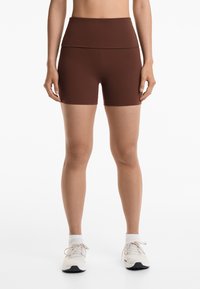 Brown high-waisted shorts made of stretchy fabric, designed with a smooth texture and a minimalist silhouette, suitable for athletic wear.