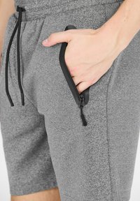 Grijze sportshorts vanTextuurstof, met een zwarte ritszak en verstelbare trekkoordsluiting. Gedetailleerde stiksels zichtbaar.