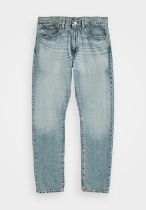 Jean en denim bleu clair de style cinq poches, fermeture avant par bouton et fermeture éclair, avec un effet délavé autour de la zone de la cuisse supérieure.