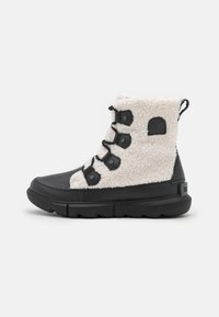 Botas de invierno en blanco y negro con un upper texturizado, cordones y una lengüeta, diseñadas para proporcionar calor y confort en climas fríos.