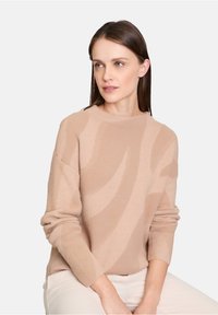 Beiger Strickpullover mit einem subtilen Wellenmuster, runder Ausschnitt und langen Ärmeln. Weiche Textur, lässiges Design, das sich gut zum Schichten eignet.