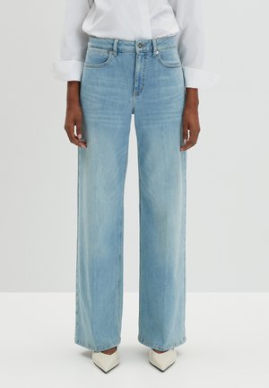 Jean large bleu clair en denim avec une teinte moyenne. Il possède des poches avant, des passants de ceinture et une fermeture éclair.