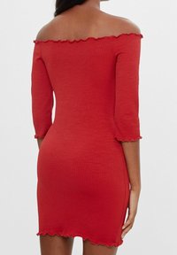 Červené žebrované šaty s odhalenými rameny, tříčtvrtečními rukávy a vroubkovanými okraji, s přiléhavým střihem.