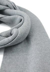 Sciarpa grigia lavorata a maglia con una texture morbida, caratterizzata da un motivo a coste e bordi arricciati, adagiata su uno sfondo bianco.