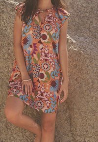 Robe à motif floral coloré avec des manches courtes, base orange, décolleté en forme de trou de serrure et coupe décontractée. Le tissu semble léger et texturé.