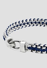 Silver-tone bracelet featuring interwoven navy blue cord and metal links. Secure clasp with a polished finish. Compact and textured design.