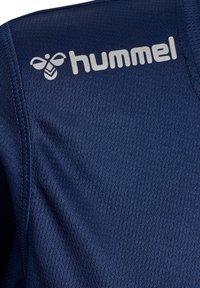 Marineblaue Sportshirt aus strukturiertem Stoff, mit einem auffälligen hellgrauen "hummel"-Logo und einem Insektenemblem auf der oberen linken Seite.