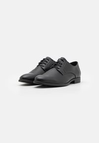Scarpe eleganti in pelle nera con punta arrotondata, design con lacci e un pannello testurizzato sul lato. Presentano un tacco basso e una superficie liscia.