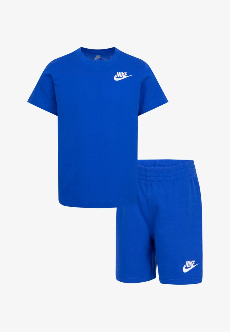 Zils kokvilnas t-krekls un šortu komplekts. T-kreklam ir apaļa kakla izgriezums un īsas piedurknes; abiem izstrādājumiem ir balta Nike logo. Šortiem ir elastīgs jostasvieta.