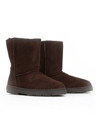 Botas de ante marrón hasta el tobillo con suela de goma, que presentan una punta redonda, una textura suave y un diseño superior alto y cónico.