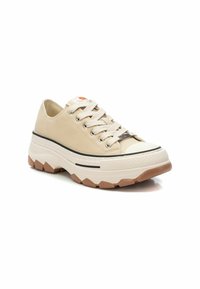 Zapatillas beige con cordones hechas de lona, con una puntera de goma y una suela de plataforma en capas que presenta un patrón texturizado y una franja negra contrastante.