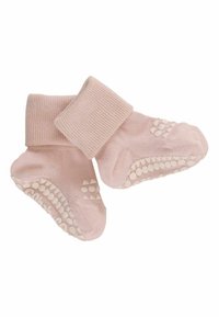 Chaussettes bébé douces rose pâle avec poignets rabattables et grip antidérapant blanc sur les semelles et les orteils, présentées sur un fond blanc.