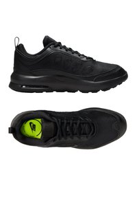 Zapatillas deportivas negras con parte superior de malla texturizada, suela de goma y un cuello acolchado. Presenta una plantilla de color verde brillante con la marca.